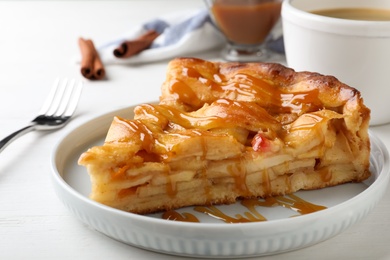 Slice of traditional apple pie on white wooden table, closeup