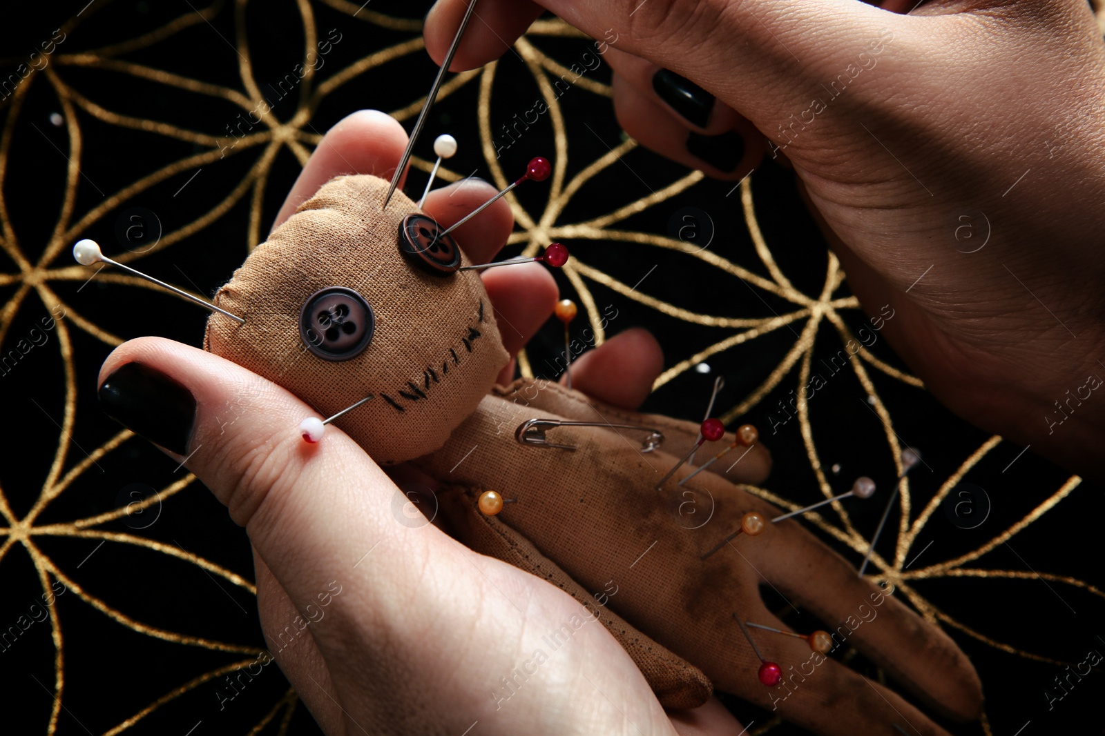 Photo of Woman stabbing voodoo doll with needle at table, closeup. Curse ceremony