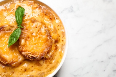 Tasty homemade french onion soup on white marble table, top view. Space for text