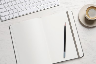 Photo of Open blank notebook, pencil, coffee and keyboard on white wooden table, flat lay