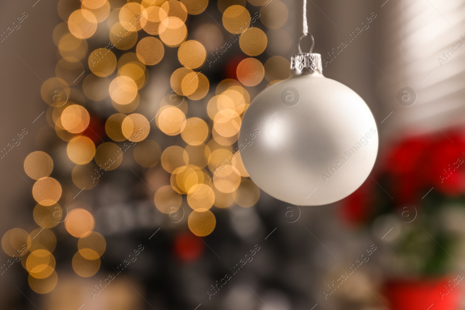 Photo of Beautiful holiday ornament hanging against blurred Christmas lights