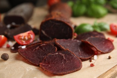 Photo of Delicious dry-cured beef basturma with spices on wooden table, closeup