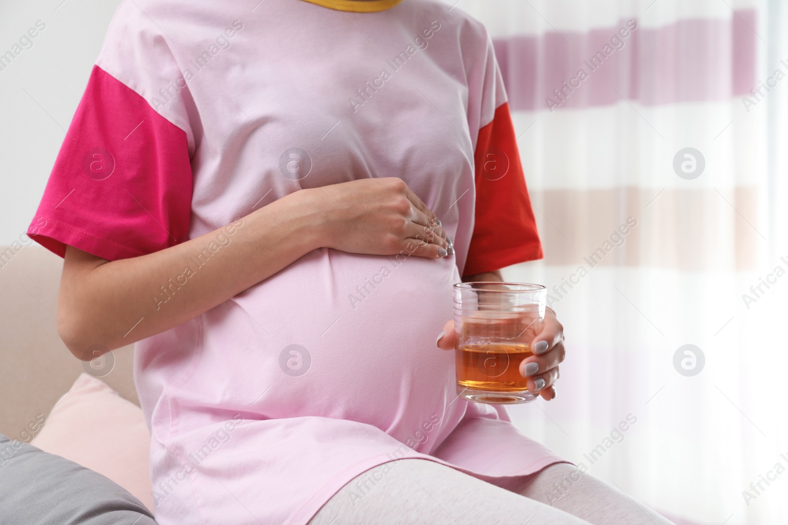 Photo of Future mother with glass of alcohol at home, closeup. Bad habits during pregnancy