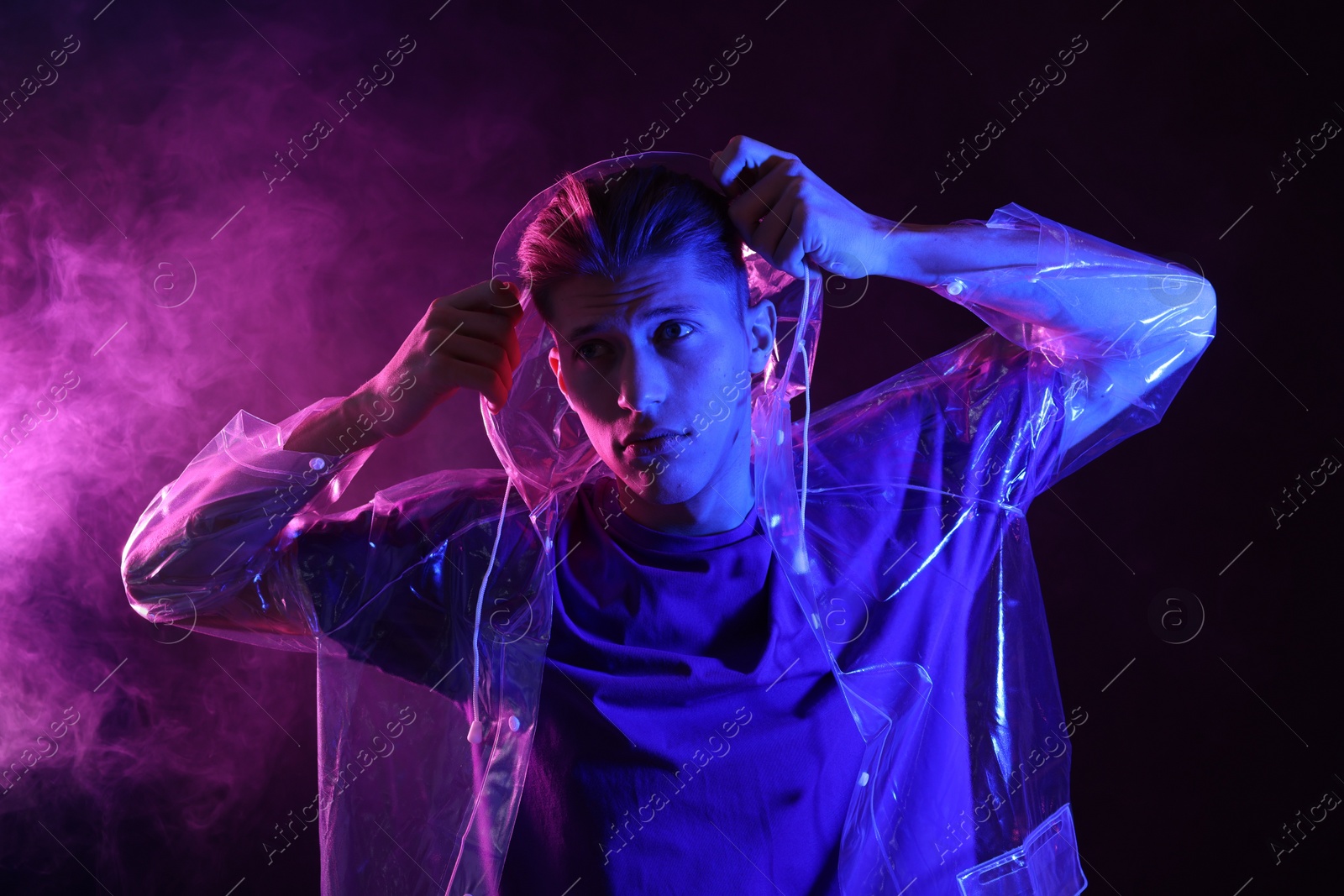 Photo of Young man wearing clear coat in neon lights with smoke effect