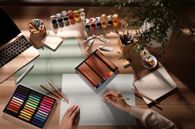 Artist drawing with pastel pencil at table, top view