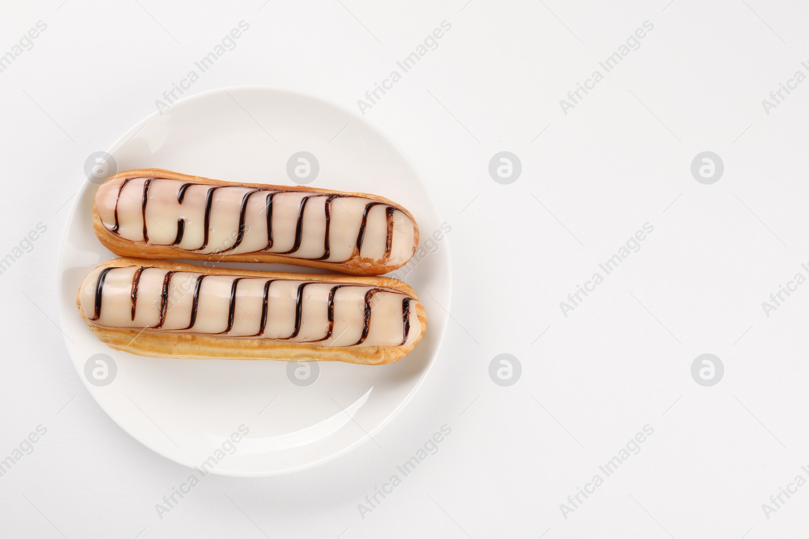 Photo of Delicious eclairs covered with glaze on white background, top view