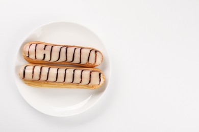 Delicious eclairs covered with glaze on white background, top view