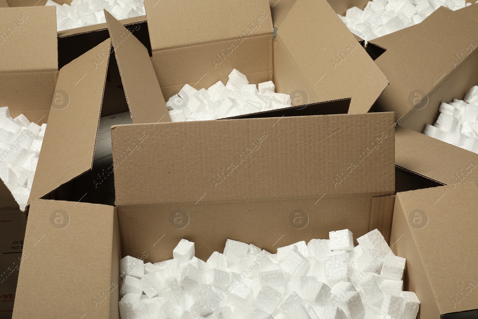 Photo of Open cardboard boxes with pieces of polystyrene foam on floor. Packaging goods