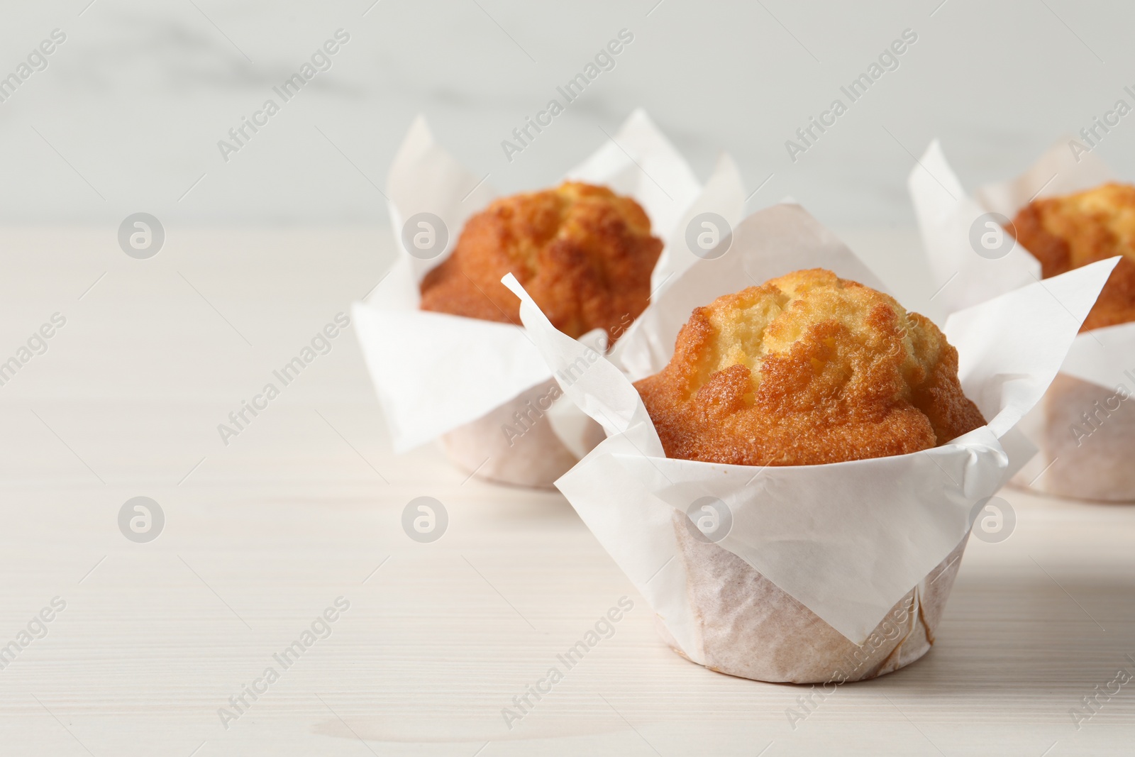 Photo of Tasty muffins on white wooden table, closeup. Space for text