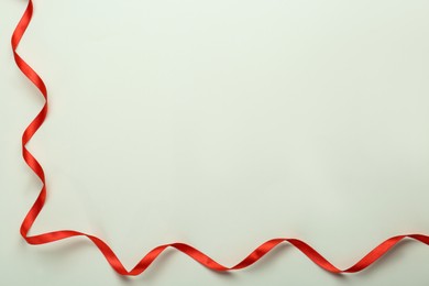 Photo of Beautiful red ribbon on white background, top view. Space for text
