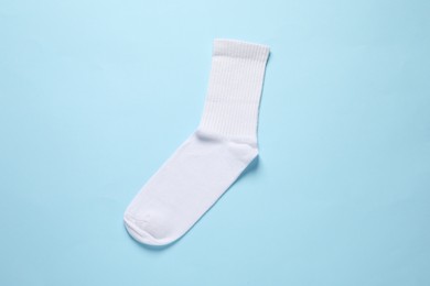 One white sock on light blue background, top view