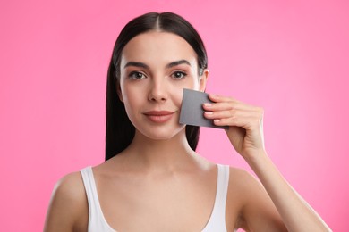 Photo of Beautiful woman using mattifying wipe on pink background