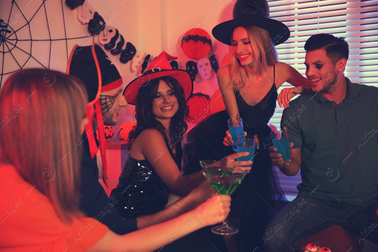 Photo of Group of friends toasting with cocktails at Halloween party indoors