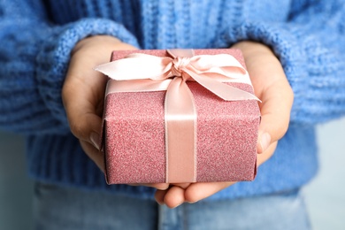 Young woman holding Christmas gift, closeup view