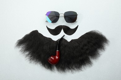 Photo of Flat lay composition with artificial moustache and sunglasses on light grey background