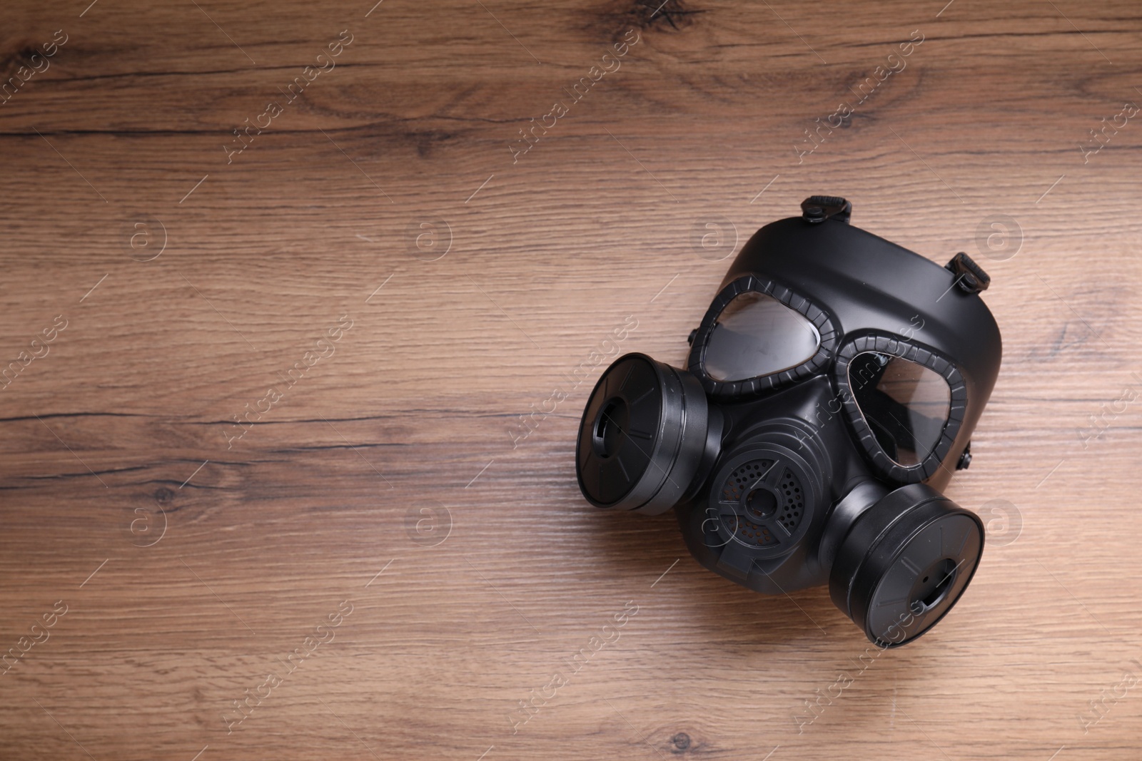 Photo of One gas mask on wooden background, top view. Space for text