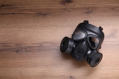 Photo of One gas mask on wooden background, top view. Space for text