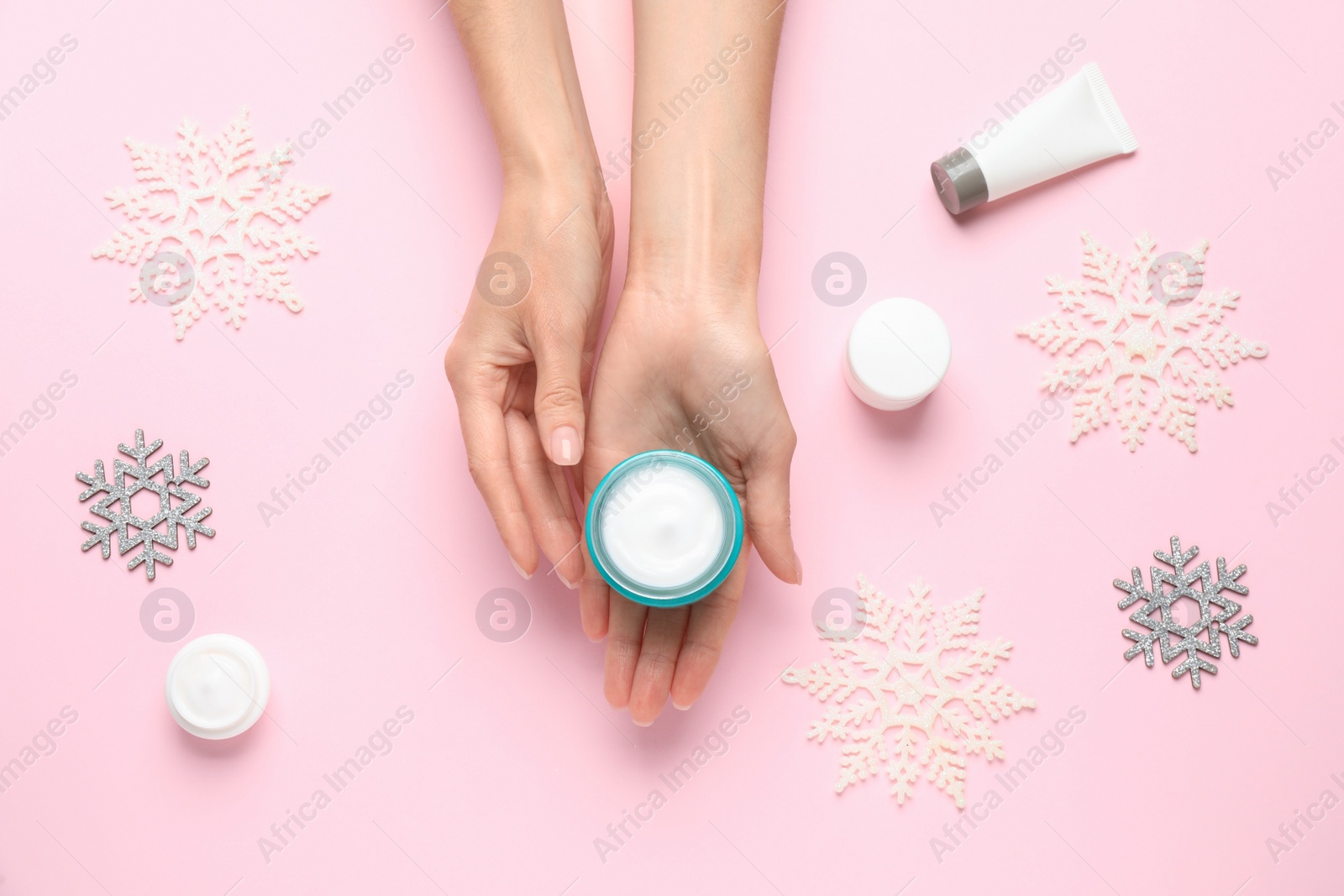 Photo of Woman with jar of hand cream at pink background, top view