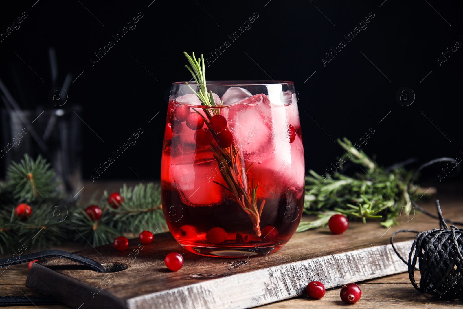 Photo of Tasty refreshing cranberry cocktail with rosemary on wooden table