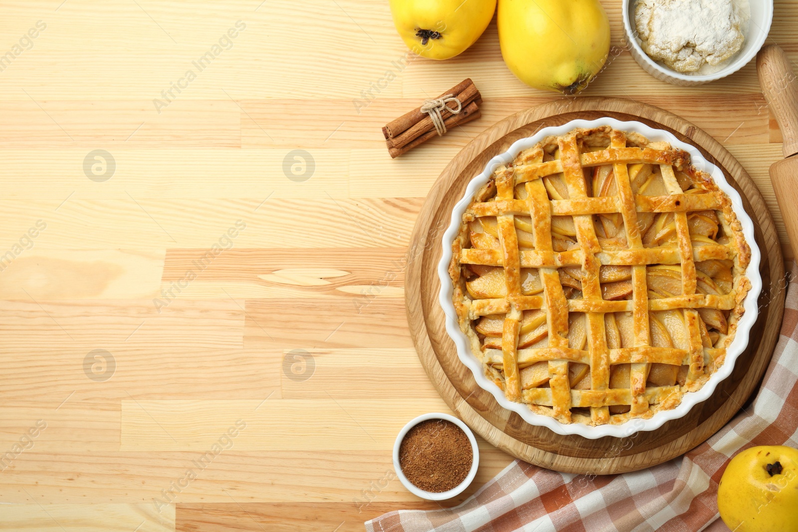 Photo of Tasty homemade quince pie and ingredients on wooden table, flat lay. Space for text