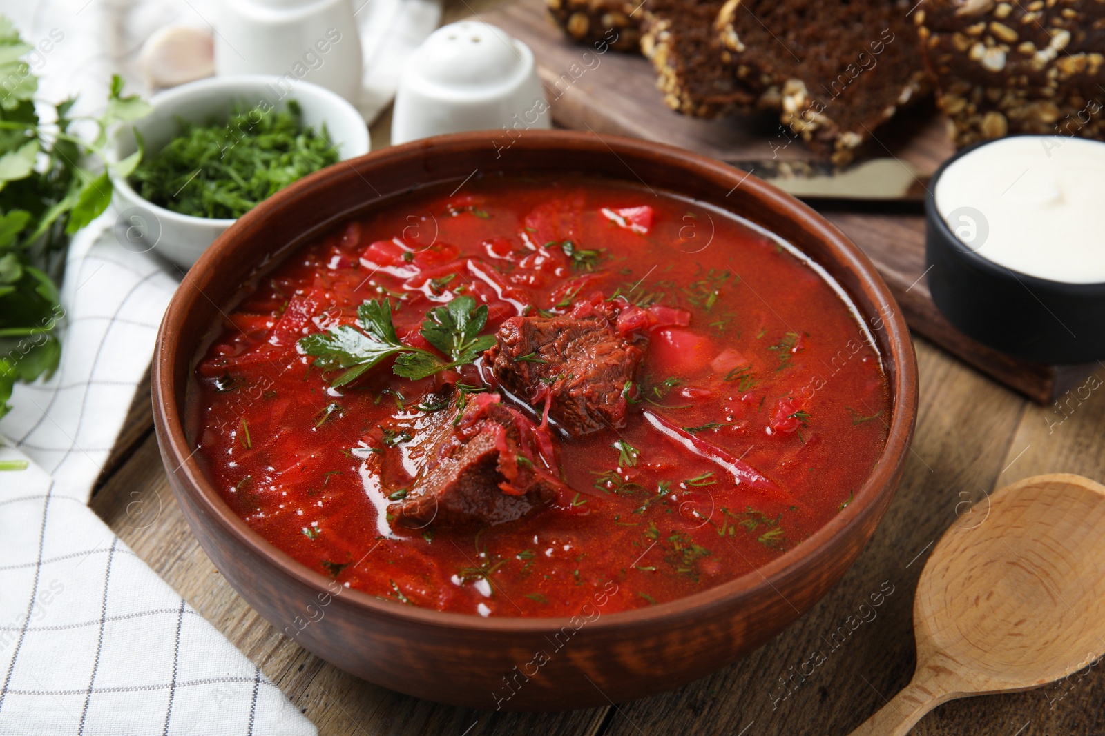 Photo of Stylish brown clay bowl with Ukrainian borsch on wooden table