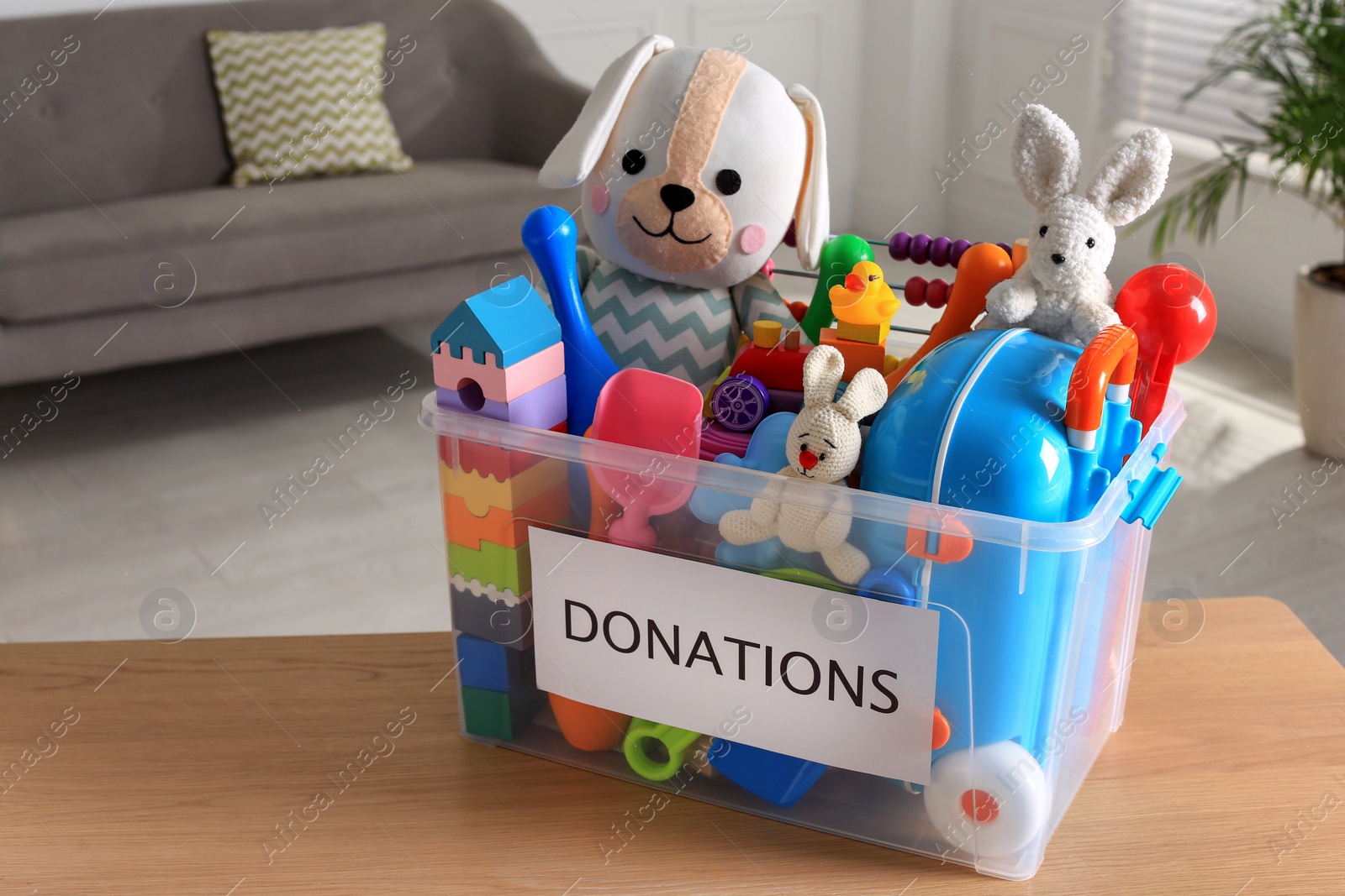 Photo of Donation box with different child toys on wooden table at home