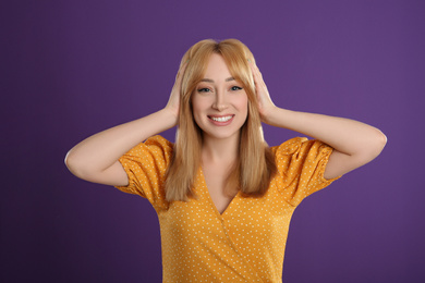 Photo of Beautiful young woman with blonde hair on purple background