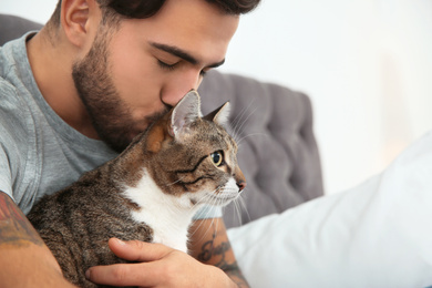 Photo of Man with cat on bed at home. Friendly pet