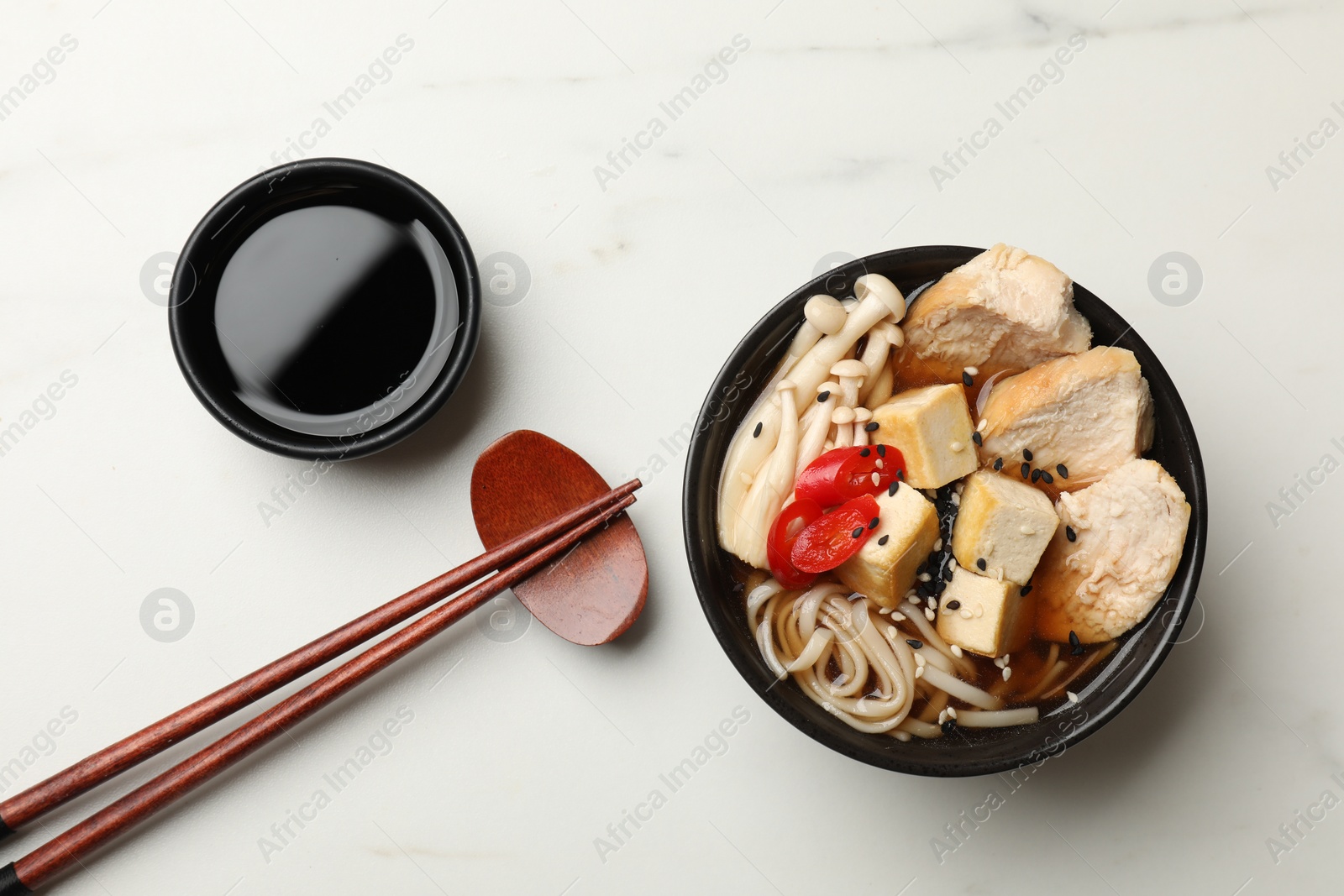 Photo of Delicious ramen served on white marble table, flat lay. Noodle soup