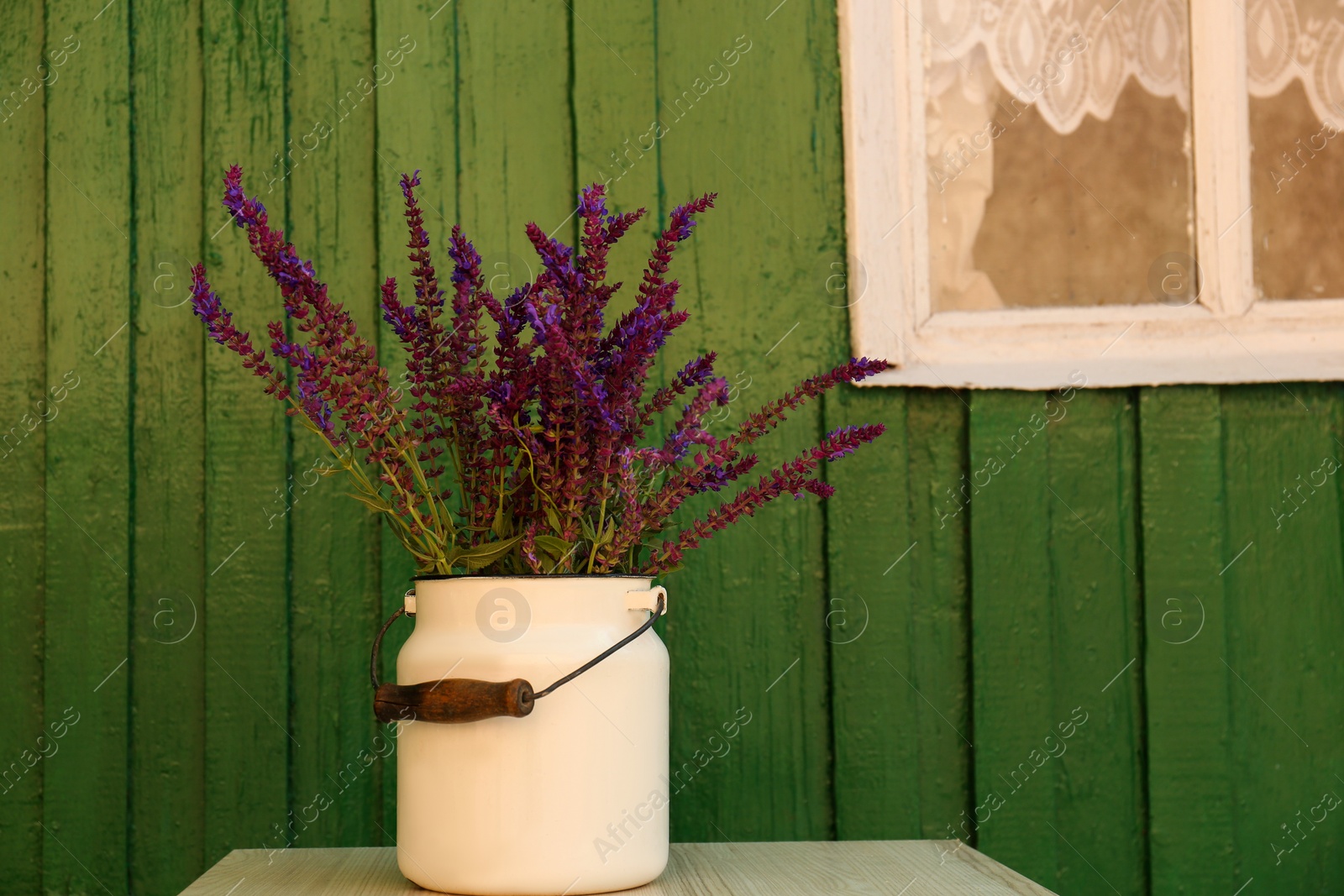 Photo of Beautiful bouquet with field flowers in can on white wooden table