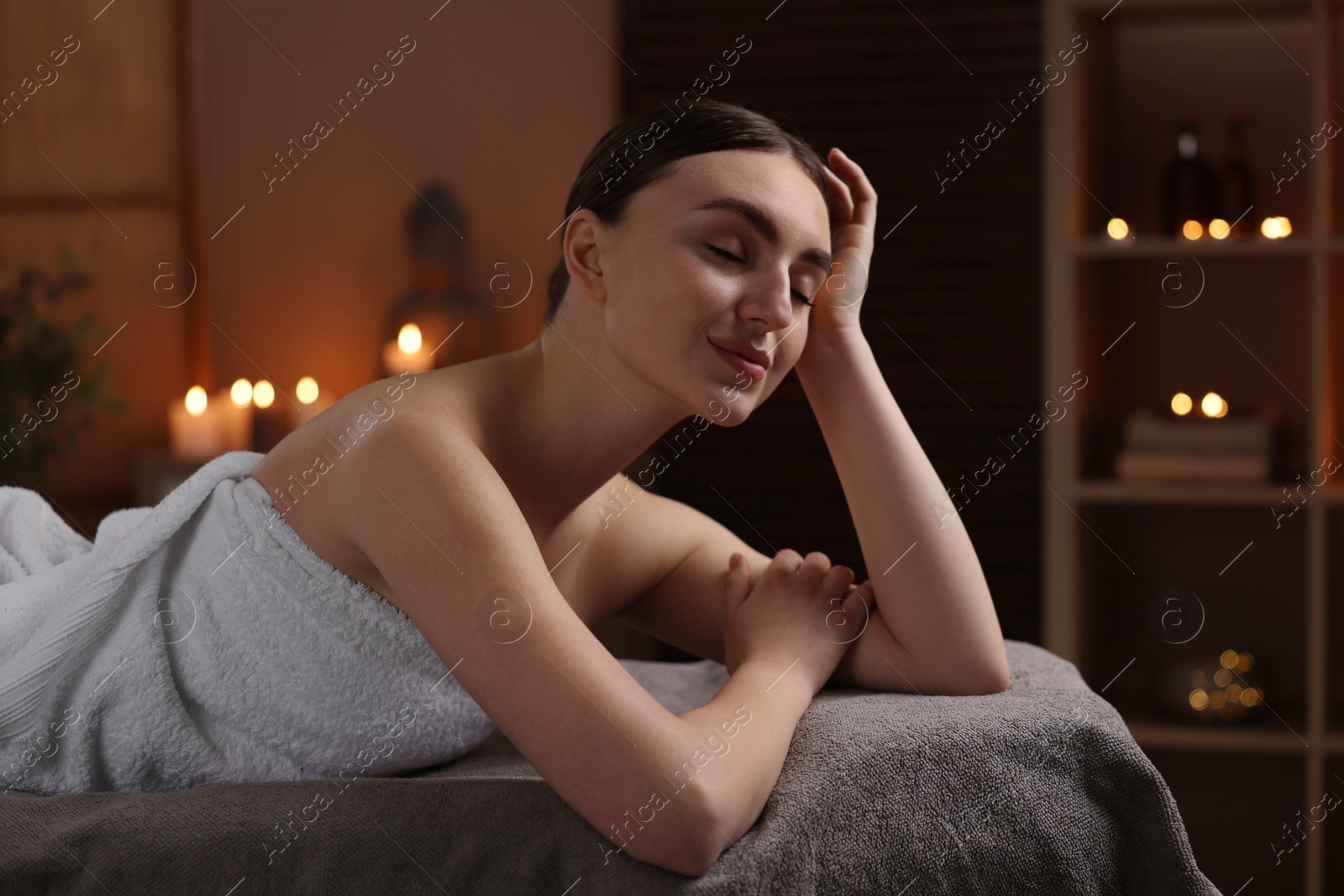 Photo of Spa therapy. Beautiful young woman lying on massage table in salon