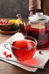 Photo of Tasty hot cranberry tea and fresh berries on wooden table