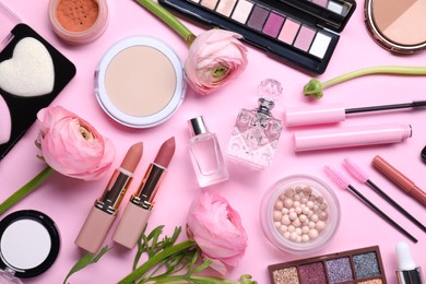 Flat lay composition with different makeup products and beautiful spring flowers on pink background