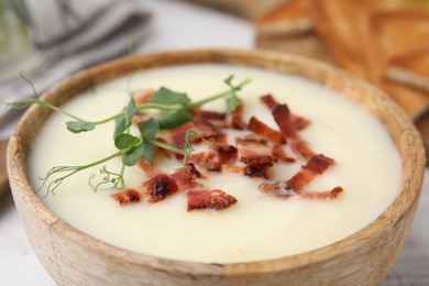 Delicious potato soup with bacon and microgreens in bowl on table, closeup