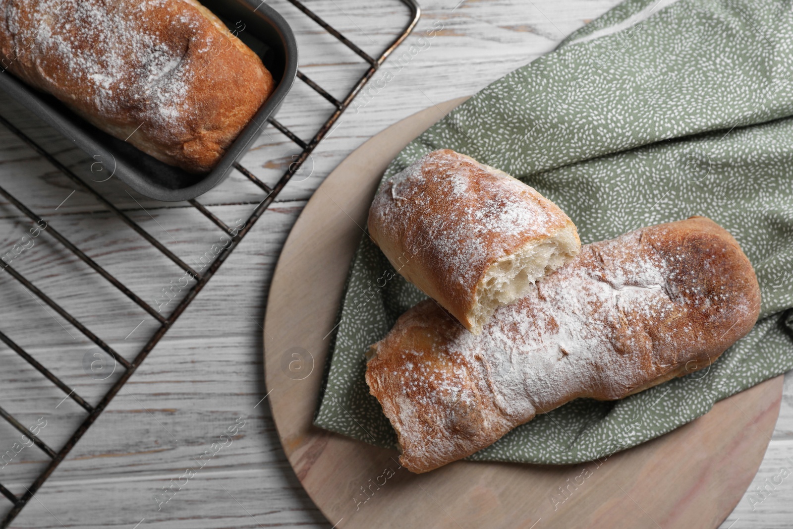 Photo of Fresh crispy ciabattas on white wooden table, flat lay