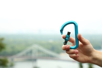 Photo of Man holding metal carabiner outdoors, closeup. Space for text