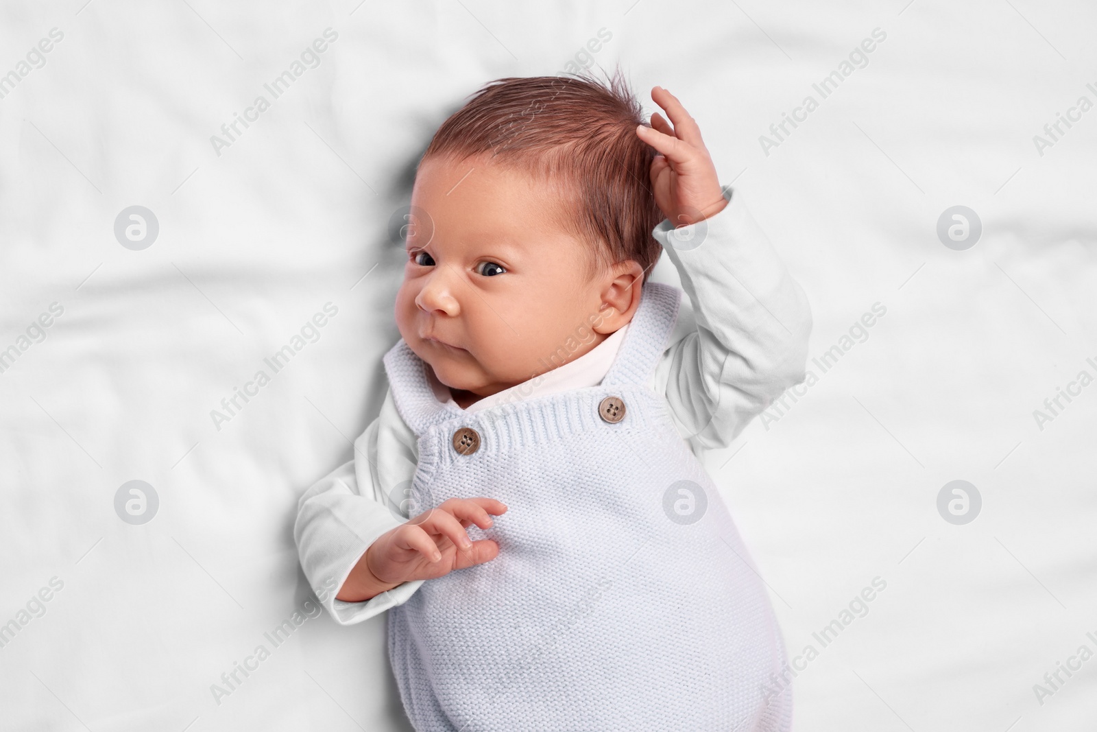 Photo of Cute newborn baby lying on white blanket, top view