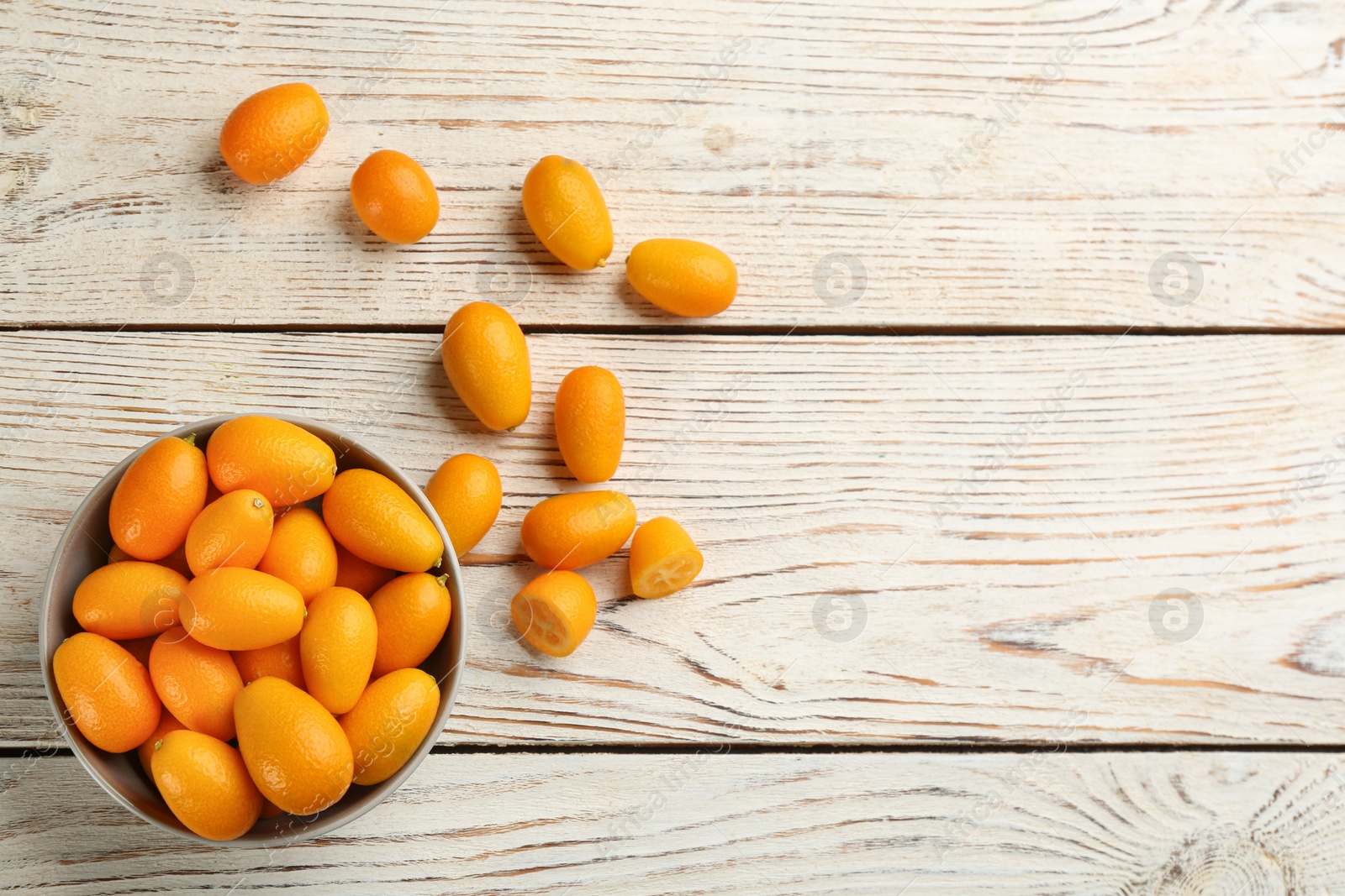 Photo of Fresh ripe kumquats on white wooden table, flat lay. Space for text