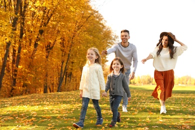 Photo of Happy family with little daughters having fun in park. Autumn park