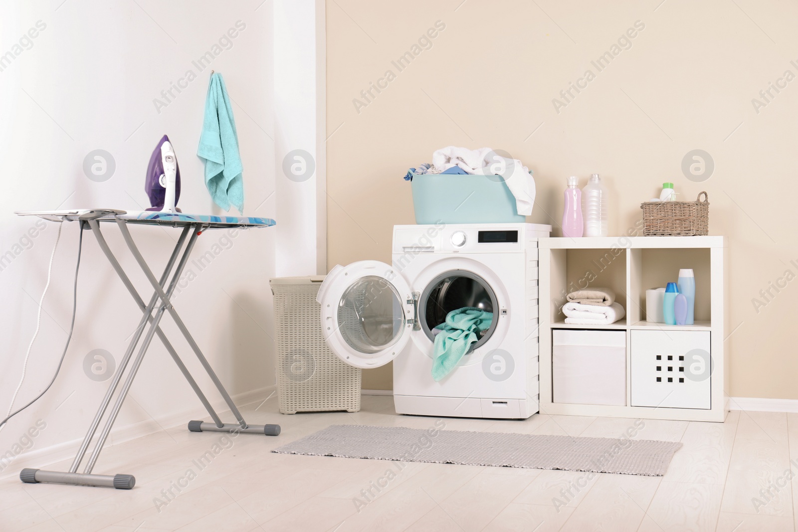 Photo of Washing machine with towels in laundry room interior