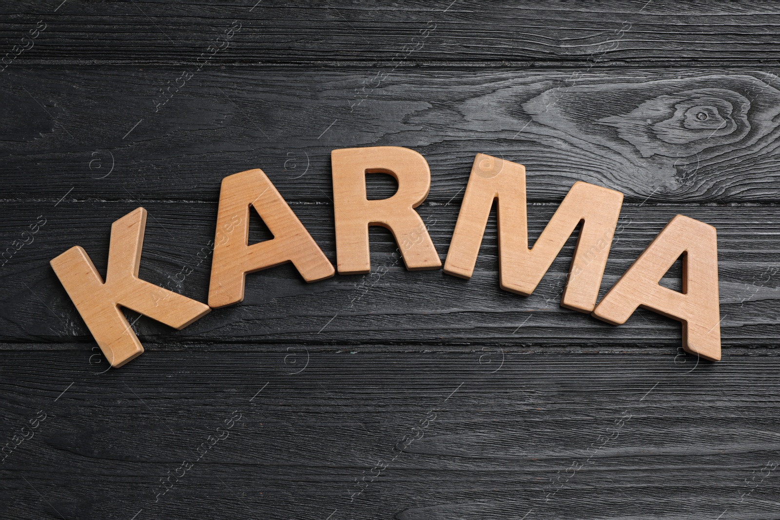 Photo of Word Karma made with wooden letters on black background, top view