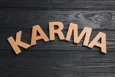 Photo of Word Karma made with wooden letters on black background, top view