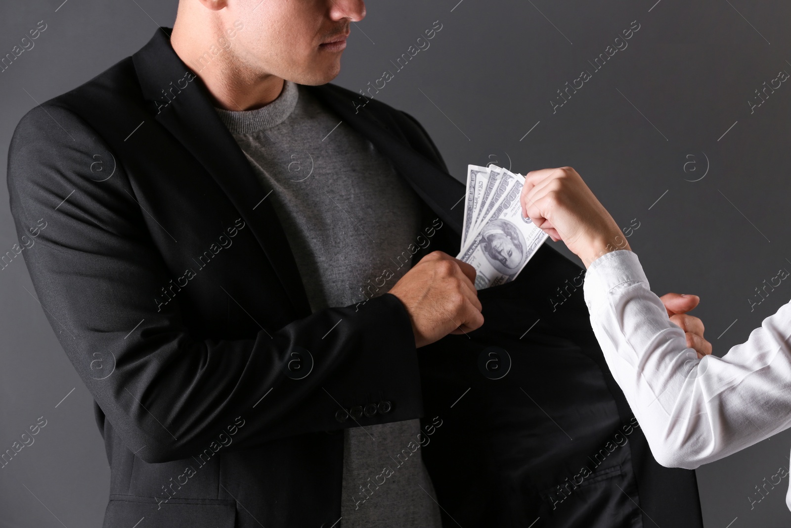 Photo of Woman giving bribe money to man on dark background, closeup