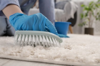 Photo of Woman cleaning carpet with brush indoors, closeup. Space for text