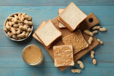 Photo of Delicious toasts with peanut butter and nuts on light blue wooden table, flat lay