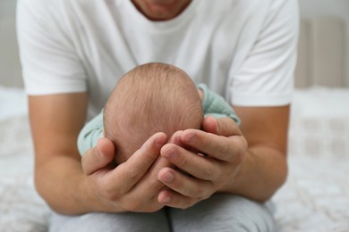 Father holding his cute baby on bed at home, closeup