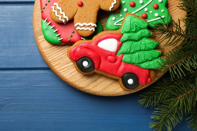 Photo of Different tasty Christmas cookies and fir tree branches on blue wooden table, flat lay. Space for text