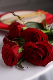 Photo of Beautiful red roses on white table indoors, closeup