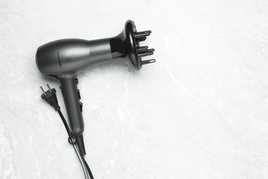 Photo of Hair dryer and space for text on light marble table, top view. Professional hairdresser tool