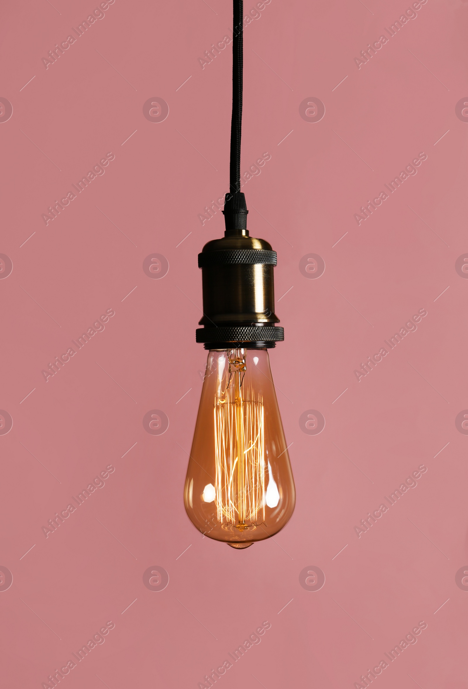 Photo of Hanging modern lamp bulb against pink background